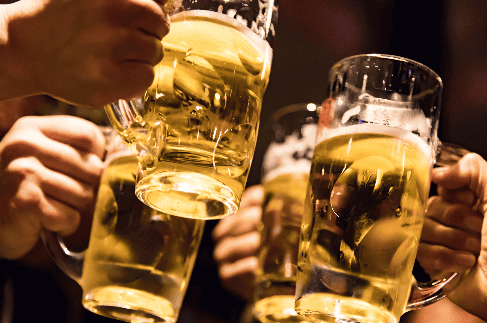 Hands raise frosty mugs of golden beer in a celebratory toast, capturing the lively spirit of an izakaya night in Singapore. The dim, warm lighting and bubbling foam evoke camaraderie, laughter, and the shared joy of good drinks and great company.