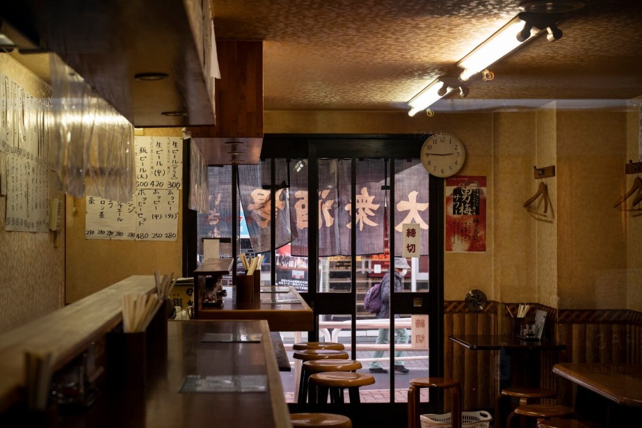 A photo of the interior design of an Izakaya, warm lighting, seats fixed next to each other.