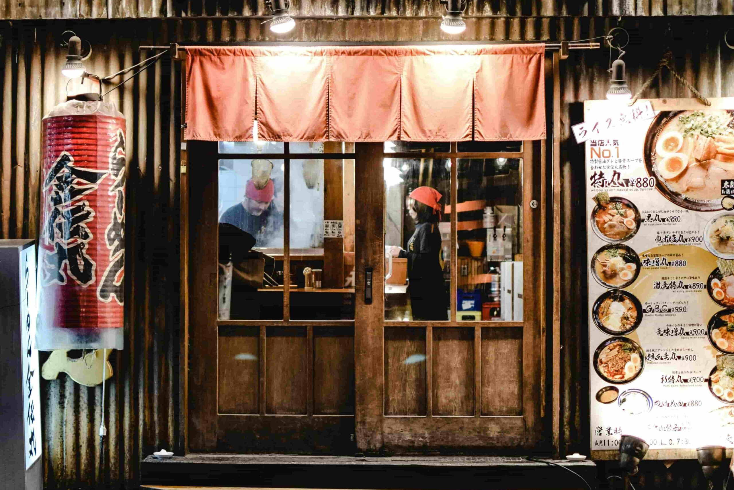 An image of a traditional Izakaya during the evening hours with its wood-paneled interior and door.
