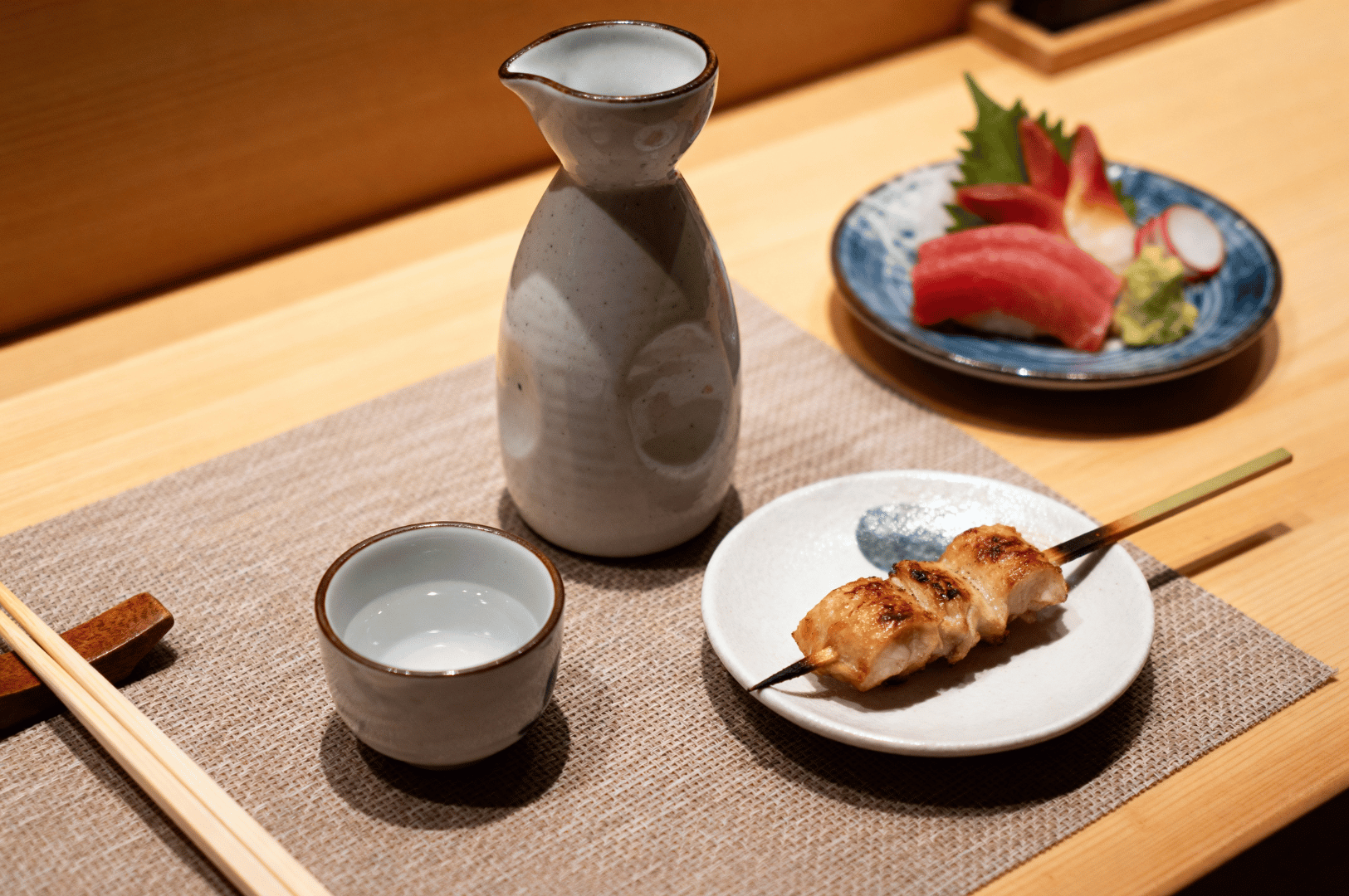 Traditional Japanese meal setting at a Novena izakaya in Singapore, featuring cold sake, grilled skewers, and assorted sashimi—showcasing the refined presentation and rising appeal of Japan-style dining in the city’s vibrant food scene.
