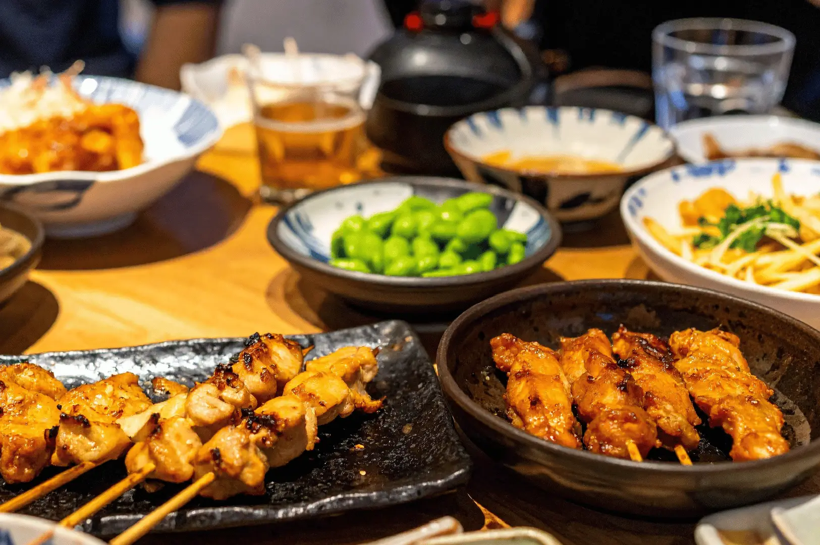A variety of Japanese dishes including yakitori skewers, edamame, and side dishes at Best Izakaya Singapore