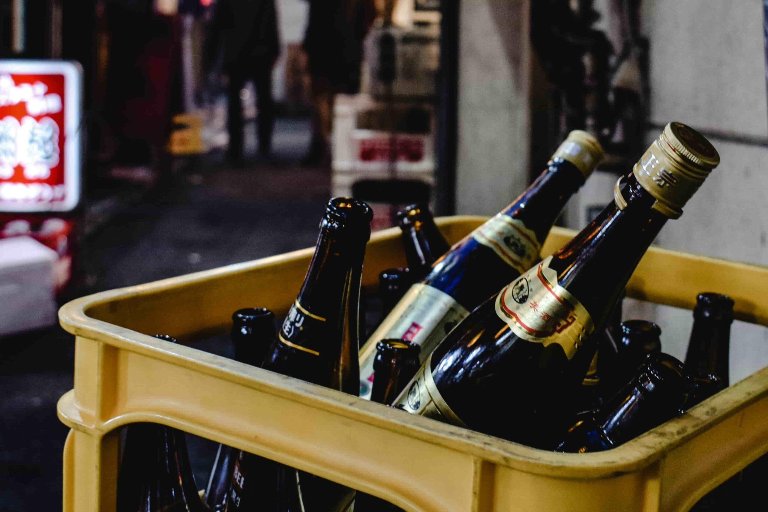 A photo of a basket of Japanese beers in an alley way filled with different Izakaya stalls.