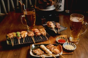Yakitori skewers and beer served on a traditional izakaya table.