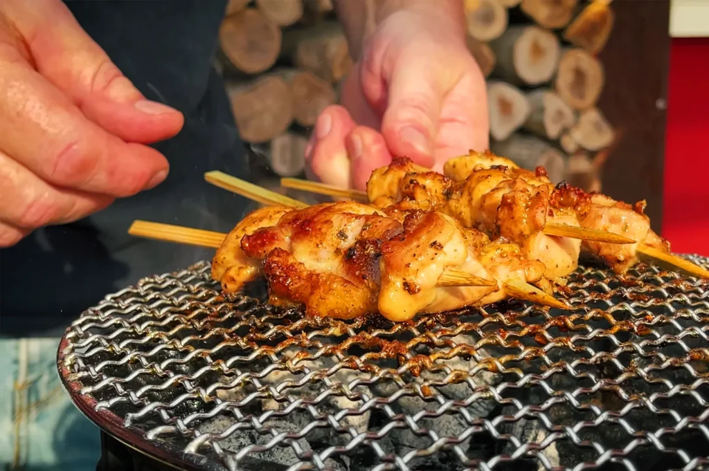 Close-up of yakitori skewers grilling over charcoal