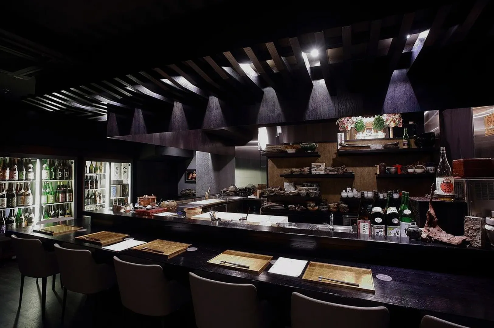 Modern Japanese izakaya counter bar with sake bottles and seating