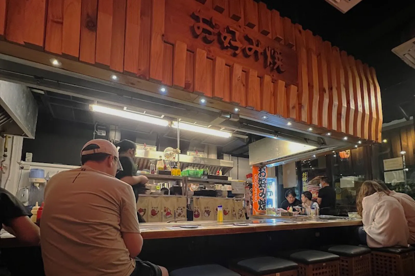 Casual Japanese izakaya street-style counter with diners