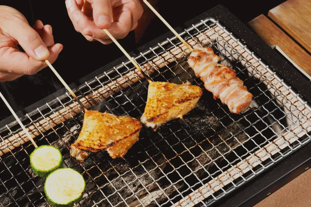 Japanese yakitori skewers grilling over charcoal with chicken and vegetables