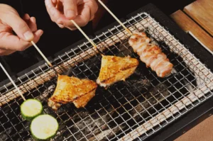 Japanese yakitori skewers grilling over charcoal with chicken and vegetables