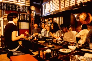 Singapore izakaya interior with diners enjoying yakitori skewers and drinks, warm lighting casual Japanese dining atmosphere shared table experience