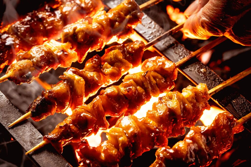 yakitori skewers grilling over charcoal fire in Singapore izakaya, showcasing timing and heat control for perfect texture and flavor