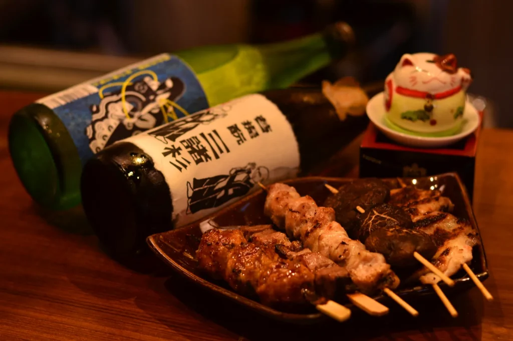 yakitori skewers with sake bottle Singapore izakaya grilled chicken and mushrooms Japanese bar dining setup
