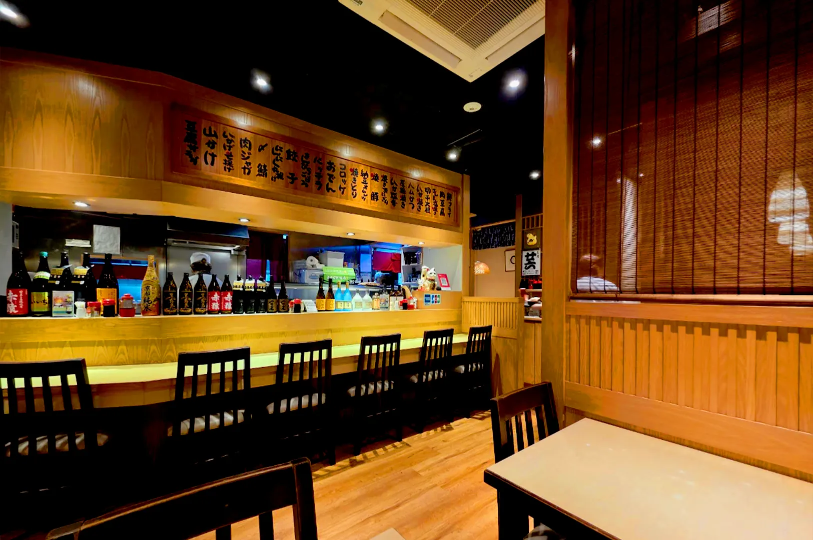 Shinjuku Restaurant Cuppage Plaza bar counter seating Japanese izakaya Singapore warm lighting sake bottles interior