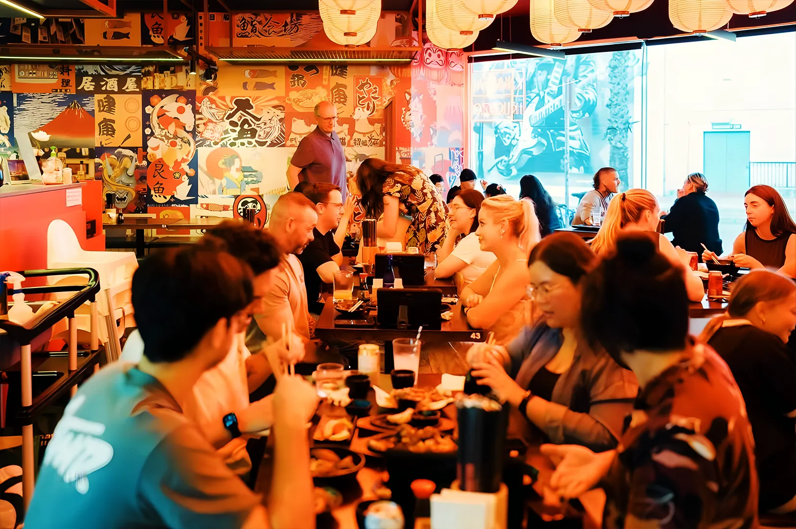 Busy izakaya dining scene in Somerset Singapore with vibrant crowd, lantern lights and shared dishes
