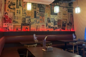 Empty izakaya interior with neon dragon sign and red ambient lighting.