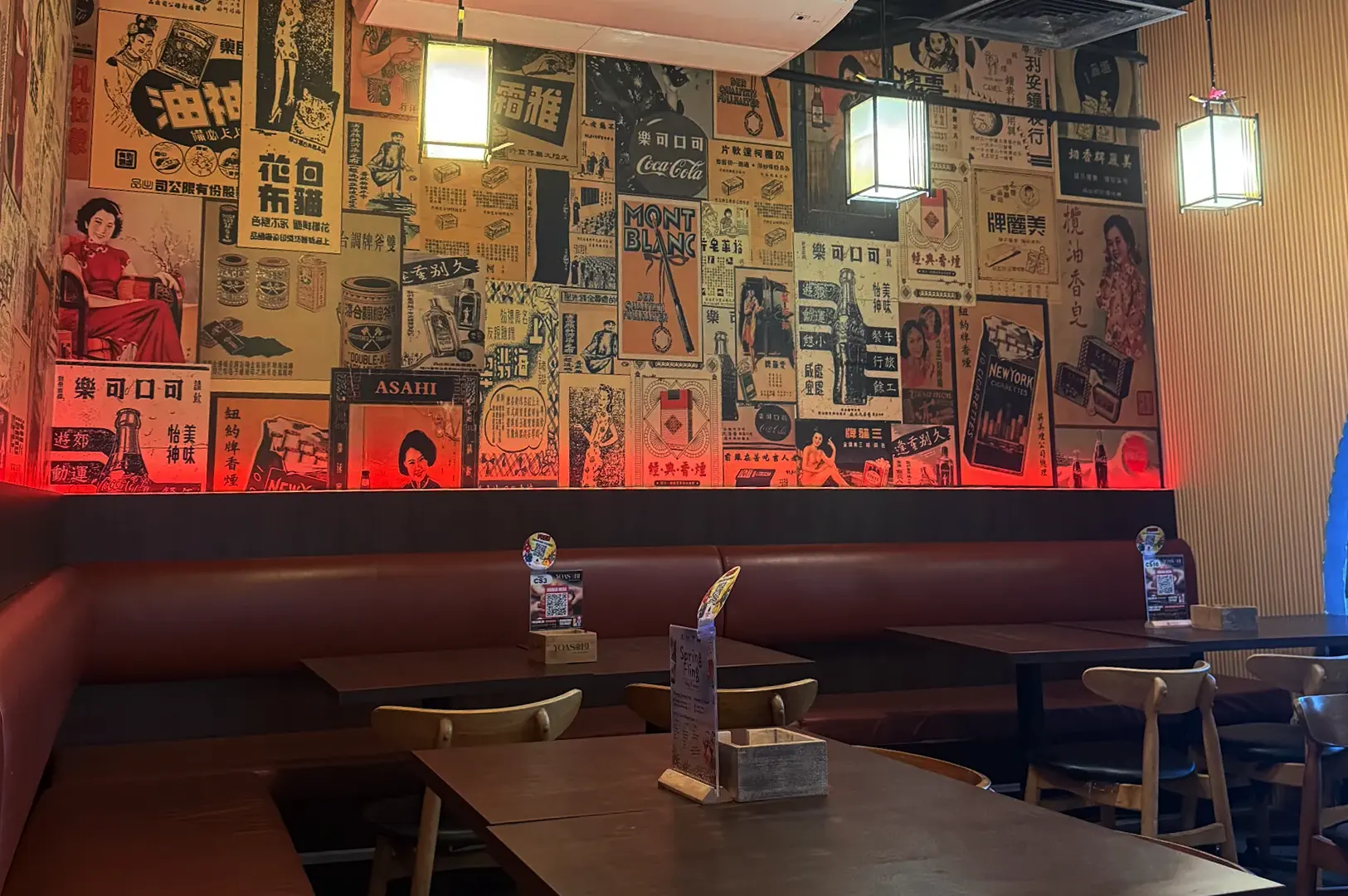 Empty izakaya interior with neon dragon sign and red ambient lighting.