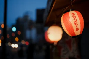 Red paper lanterns at dusk with bokeh lights.