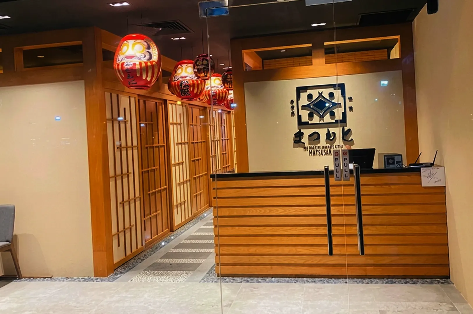 Entrance of Izakaya Matsumoto with wooden counter and shoji screens.