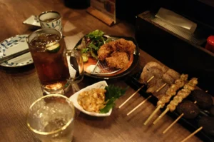 Izakaya table with drinks, karaage, skewers, and small dishes.
