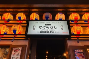 NININGASHI entrance sign framed by red and yellow lanterns.