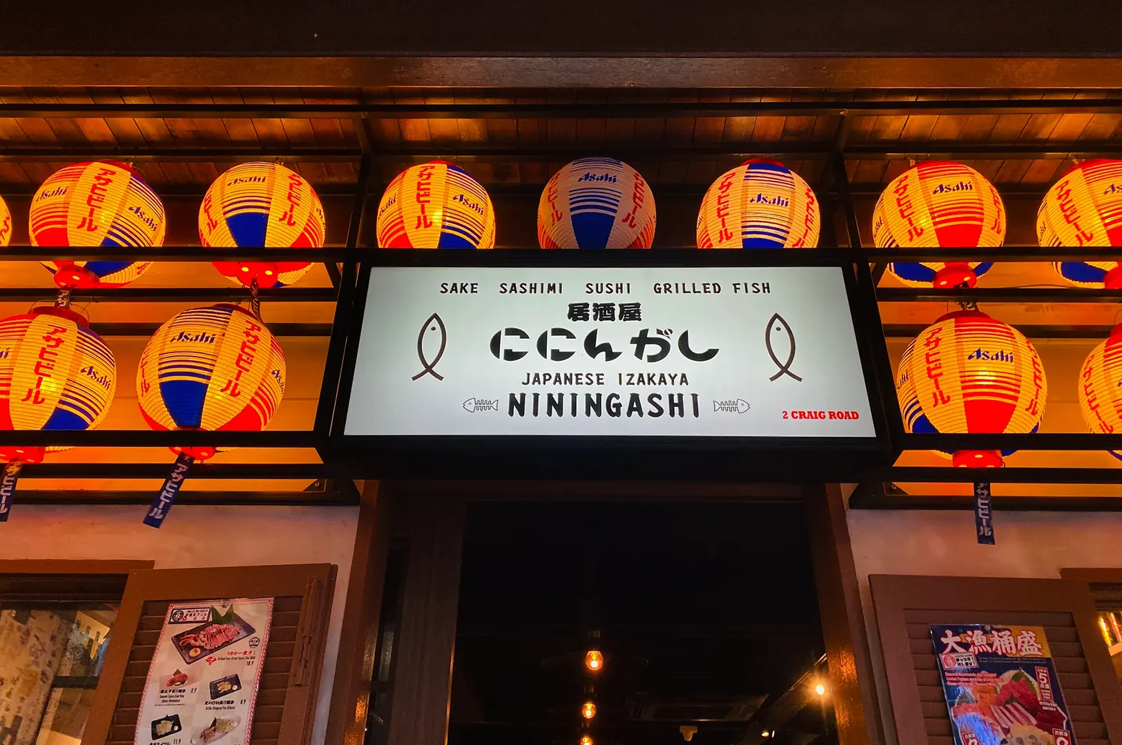 NININGASHI entrance sign framed by red and yellow lanterns.
