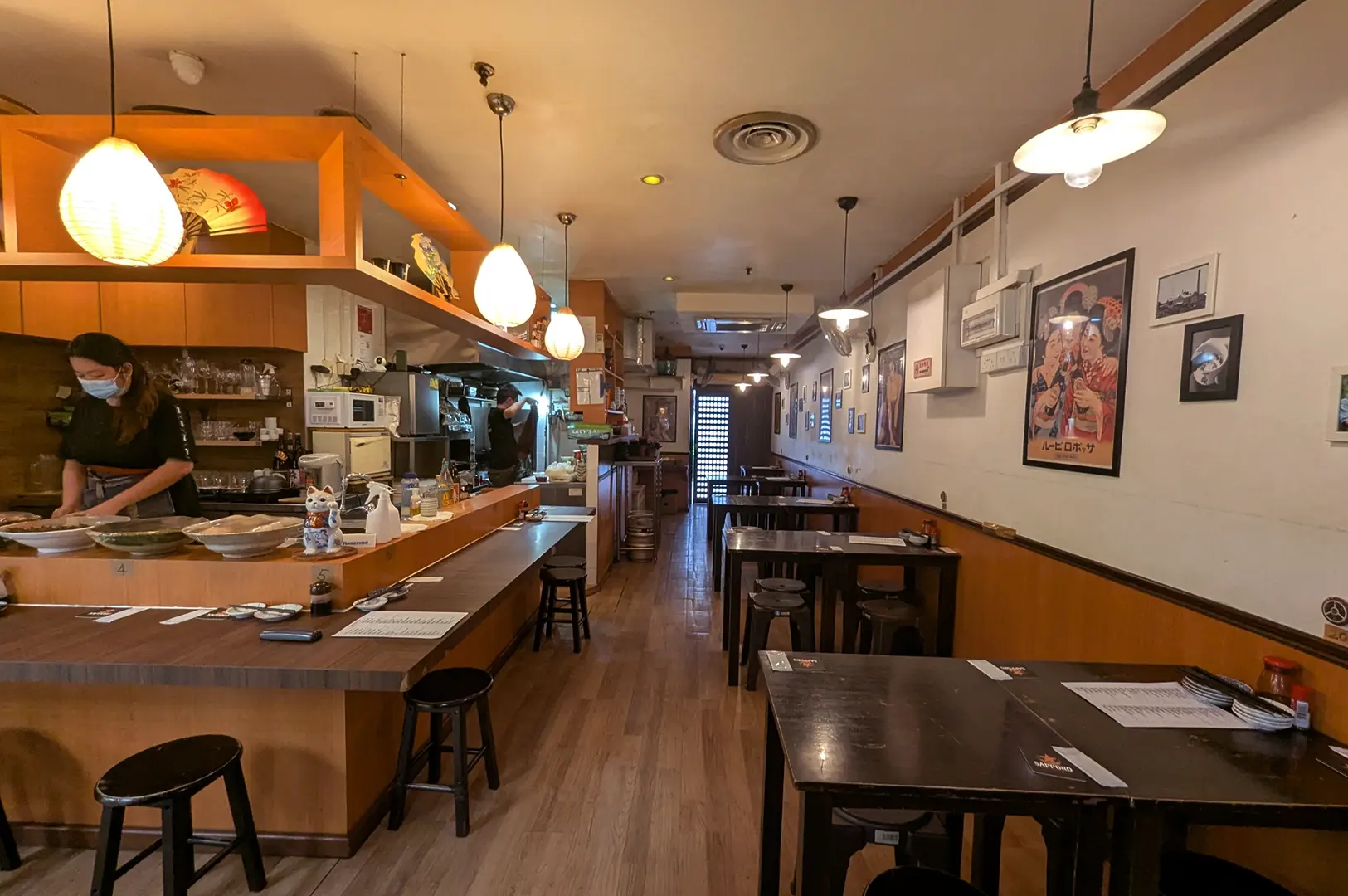 Sushi bar interior with tables, wall art, and staff behind the counter.