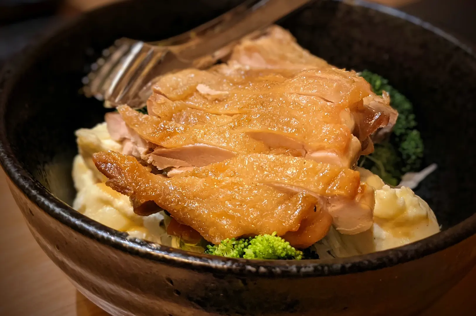 Grilled chicken over rice in black bowl.