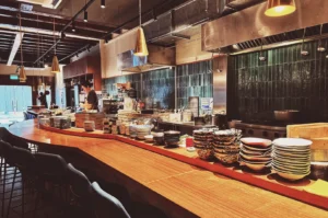 HEARTH Irori & Oden Izakaya counter with stacked plates and warm lighting.
