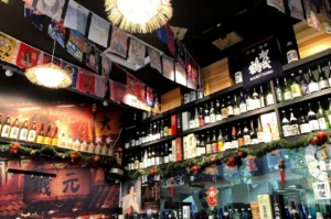 Nanami Izakaya interior with sake shelf, decorations, and colorful signage.