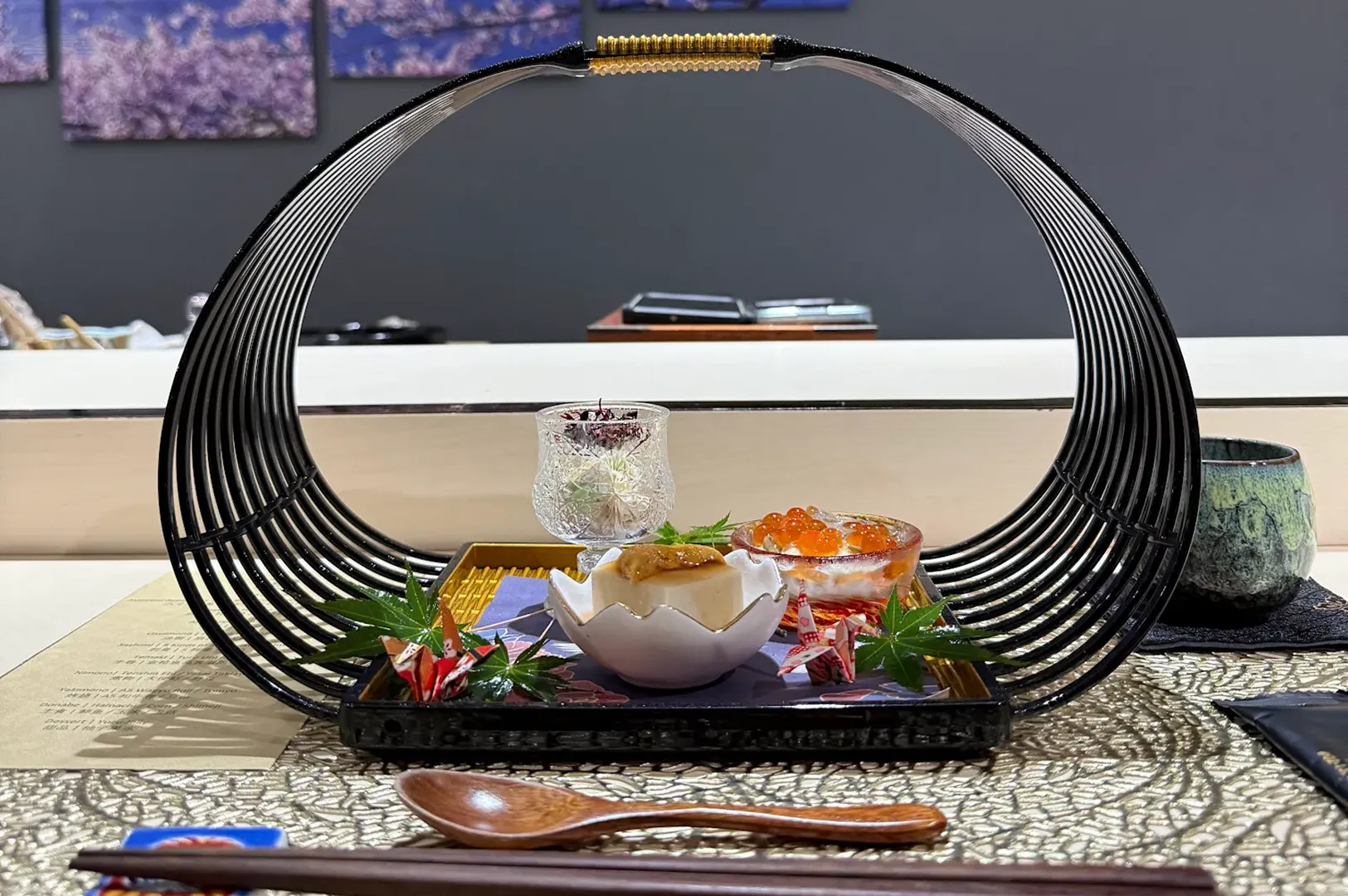 Assorted sashimi plate with tuna, white fish, uni, shiso leaves, and edible flowers on a patterned ceramic dish.