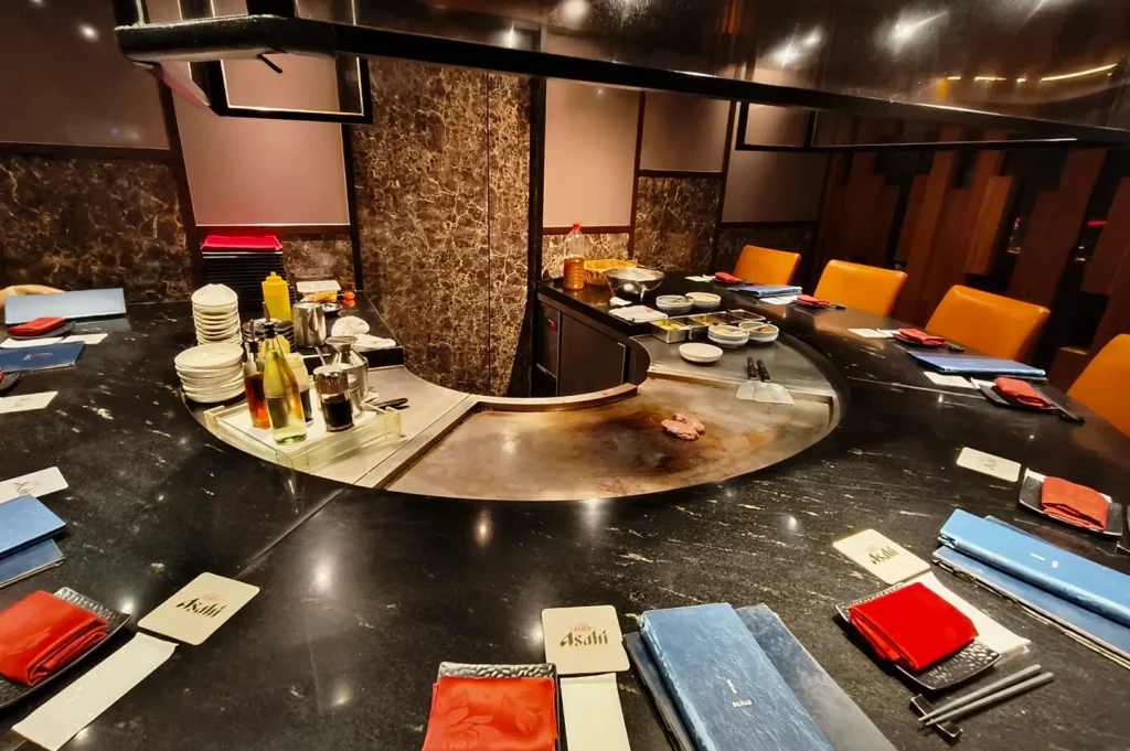 Teppanyaki counter with place settings, condiments, and central grill.
