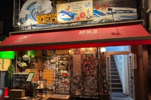 Kaikaya by the Sea storefront with a red awning and a sticker-covered entrance.