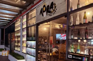 Tora Tora Tora restaurant entrance with illuminated bottle displays and dining area visible through glass doors.